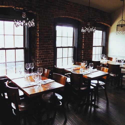 Empty Restaurant With Wooden Tables And Brick Wall